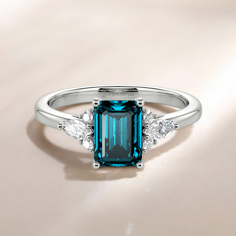 emerald-cut side-stone engagement ring with Swiss blue center stone