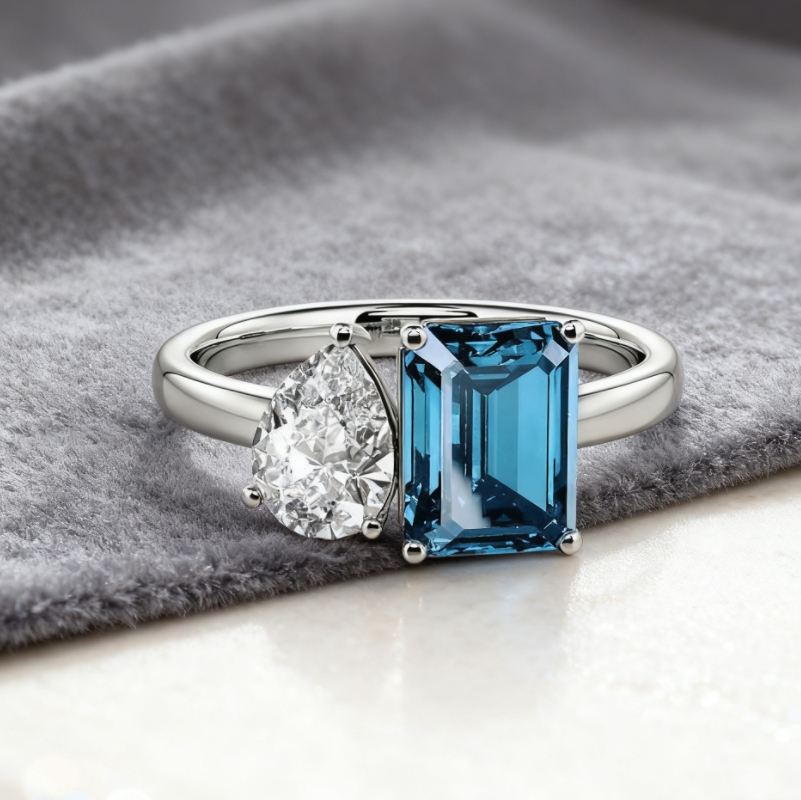 A two-stone ring with an emerald cut and a pear cut diamond, set in white gold
