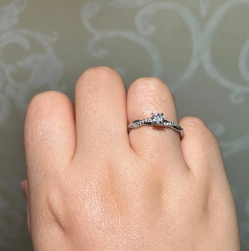 Moissanite promise ring on hand showing thin gold band with small center stone