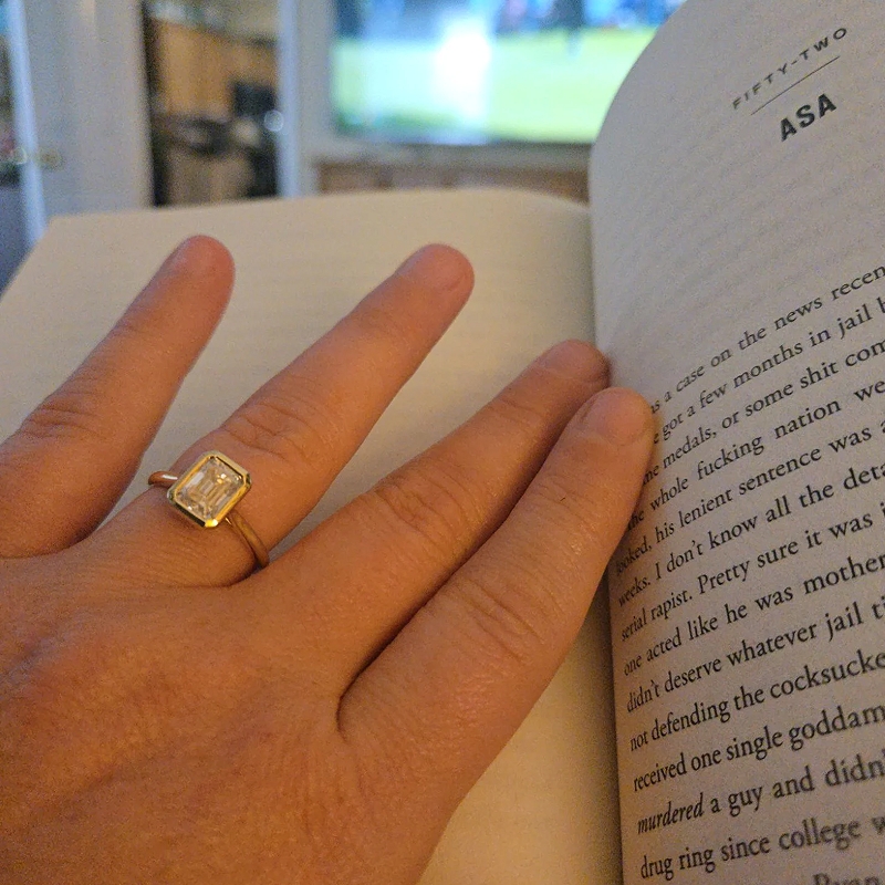 Emerald cut bezel set engagement ring worn on hand