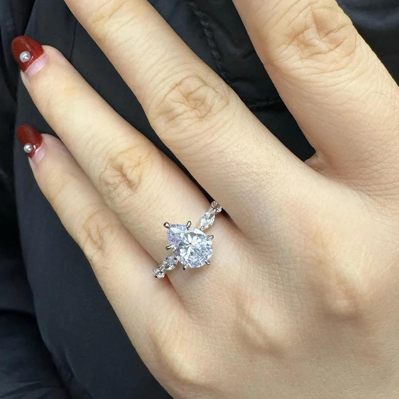 Pear‑cut mossinate engagement ring on hand