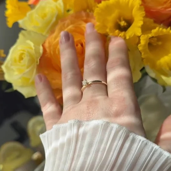 Hand wearing a thin gold promise ring